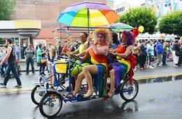 People in colorful outfits riding on a 4 person bike with an umbrella