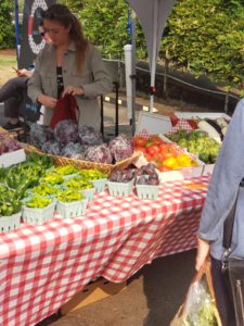 Various produce on a table with shoppers